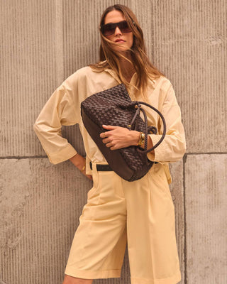 Woman carrying chocolate woven shoulder tote