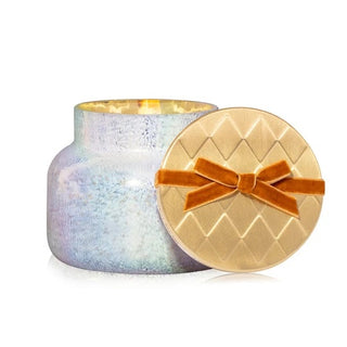 an iridescent jar with a gold lid and copper velvet bow candle