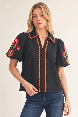 Alabama Lee Floral Top – black short sleeve collared top with orange trim and embroidered red floral sleeves