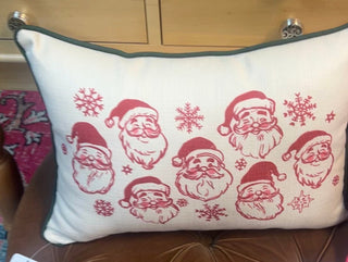 white throw pillow with red Santa faces