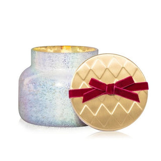 an iridescent jar with a gold lid and red velvet bow candle